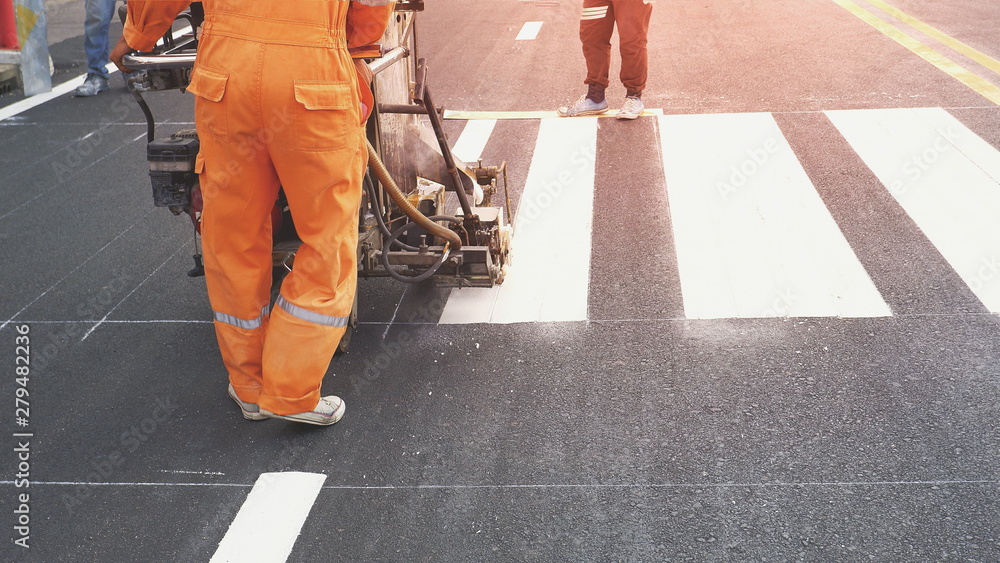 Road workers with thermoplastic spray road marking machine working to paint pedestrian crosswalk on asphalt road surface in the city - obrazy, fototapety, plakaty 