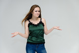 Fototapeta Młodzieżowe - Concept portrait above the knee of a pretty girl, young woman with long beautiful brown hair in a green T-shirt and blue jeans on a white background. In the studio in different poses showing emotions.