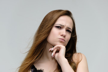 Concept close-up portrait of a pretty girl, young woman with long beautiful brown hair and beautiful face skin on a white background. In the studio in different poses showing emotions.