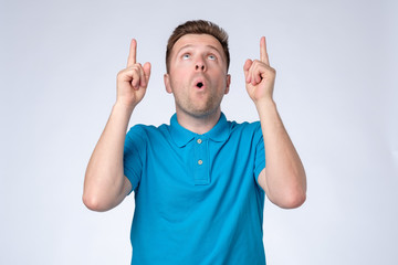 Sticker - Attractive young man in blue t-shirt pointing up with his finger