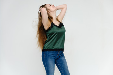 Concept portrait above the knee of a pretty girl, a young woman with long beautiful brown hair and a green t-shirt and blue jeans on a white background. In studio in different poses showing emotions.