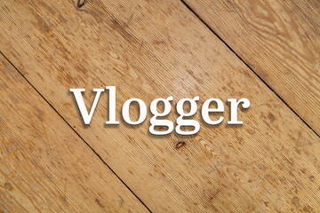 Wall Mural - `Vlogger` white text on a wooden home background. 