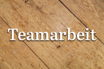 Wall Mural - `teamarbeit` white text on a wooden home background. translation: `teamwork`