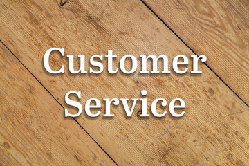 Wall Mural - `customer service` white text on a wooden home background.