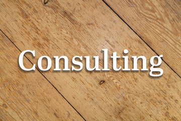 Wall Mural - 'consulting' white text on a wooden background.