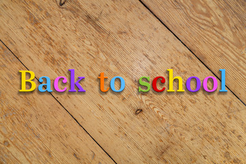 Wall Mural - `back to school` colorful text on a wooden background.