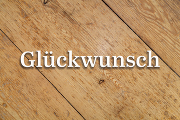 Wall Mural - `glückwunsch` white text on a wooden background. translation: `congratulations`