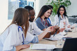 © gorynvd - Group of doctors are studying disease patient's history. Team of multiethnic young doctors having a meeting in conference room in the modern bright hospital.