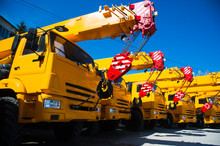 Mobile Construction Cranes With Yellow Telescopic Arms And Big Tower Cranes In Sunny Day