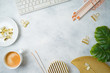 © maglara - Flat lay home office feminine table with coffee cup, golden accessories, computer keyboard and tropical leaves on grey background. Top view from above