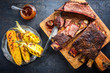 Barbecue sliced chuck beef ribs with hot rub with pineapple and corn as top view sliced on a wooden cutting board