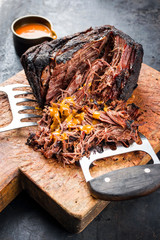 Wall Mural - Traditional barbecue wagyu pulled beef with spicy sauce as closeup on a rustic cutting board