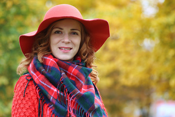 Young beautiful mother with her daughter on nature. A girl in a hat walks in the park. Girl in autumn city park in leaf fall.