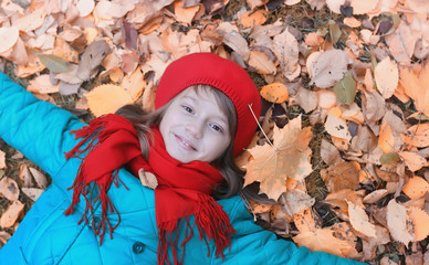 Girl in autumn city park in leaf fall. Young beautiful mother with her daughter on nature. A girl in a hat walks in the park.