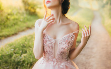Gentle Elegant Photo Of Girl With Fair Skin And Dark Hair, Cute Slender Lady With Bare Shoulders Twisted Off Straps Of Pink Peach Shiny Dress, Princess Touches Long Neck With Slender Fingers, No Face