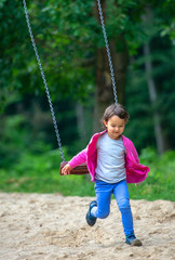 Cute little girl playing on swing in park