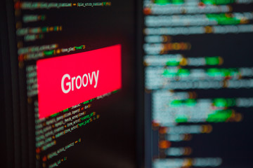 Wall Mural - programming language, groovy inscription on the background of computer code.