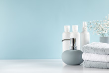 Soft Light Bathroom Decor In Pastel Blue Color, Towel, Soap Dispenser, White Flowers, Accessories On White Wood Shelf. Elegant Decor Bathroom Interior.