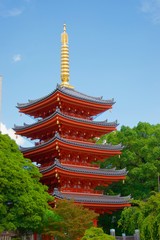 Vivid red pagoda in Fukuoka, Japan. Glowing golden spire and green trees