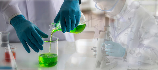 Wall Mural - laboratory concept; scientist pouring reagent from flask to beaker at table in chemistry laboratory.