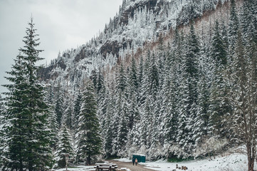 Two traveler with backpacks walk the snowy road in winter season in the distance. Tatra Mountains.