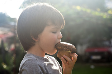 Wall Mural - Fresh porcini mushroom in child hand. Happy boy hold big cep mushroom