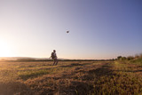 Fototapeta Kosmos - backpacker traveler walking at sunrise and throwing hat in the wind