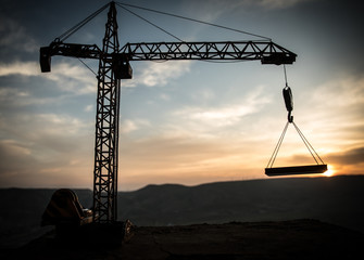 Abstract Industrial background with construction crane silhouette over amazing sunset sky. Tower crane against the evening sky. Industrial skyline