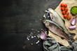 Raw fish with vegetables on a black wooden background. Fish trout. Top view. Free space for your text.