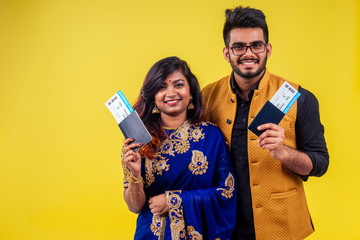happy tourist couple holding india passport with tickets on yellow background studio
