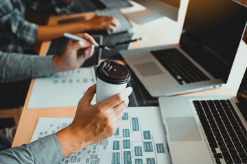 Working in the morning with businessmen are dipping coffee that works with software developers to analysis together the code written in the program on the computer.