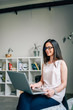 © bnenin - Young elegant woman working on laptop in modern apartment.