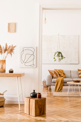 Wall Mural - Boho open space interior in cozy apartment with design gray sofa, wooden desk and coffee table, plants and elegant personal accessories. Mock up poster frame on the white wall. Stylish home decor.