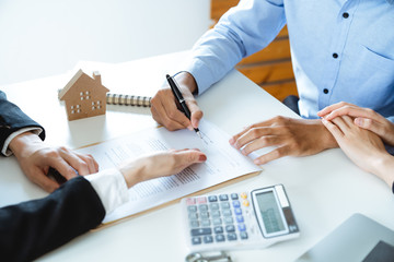 Young family couple signing home loan contract purchase agreement with property real estate agent