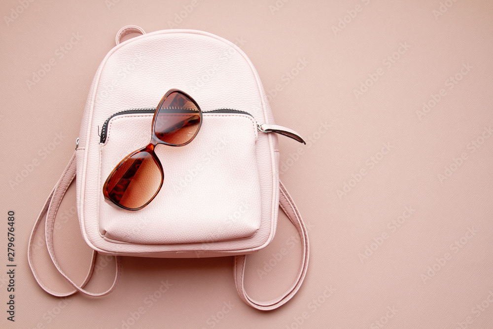 Obraz Flat lay with pink woman accessories  with backpack and woman hand holding the sunglasses. Summer fashion trends, shopping idea fototapeta, plakat