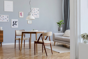 Wall Mural - Design scandinavian home interior of open space with stylish chairs, family table wooden commode, gray sofa, accessories and mock up posters gallery wall. Gray background walls. Retro cozy home decor.