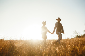 Follow me. Men leads the girl behind him. Lovely hipster couple . Couple wearing beautiful hats and sweaters. Lifestyle, happy couple of two play on a sunny day in the park.  Sunset in autumn.