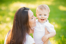 Happy Family, Young Mother With Child In Park, Kisses And Smiles Son. Sunny Day Summer