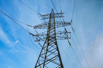 Tower of high voltage power lines against the blue sky. Electricity transmission.