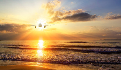 Airplane flying over blur tropical beach bokeh sun light wave and sunset sky abstract background. Copy space of business summer vacation and travel adventure concept. Vintage tone filter effect color.