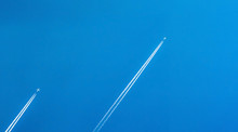 Airplane With White Condensation Tracks. Jet Plane On Clear Blue Sky With Vapor Trail. Travel By Airplane Concept. Trails Of Exhaust Gas From Airplane Engine. Aircraft With White Stripes.