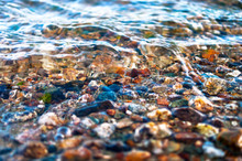 Close-up View Of Colorful Pebbles In Water Waves. Travel Concept.