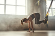 © Friends Stock - Doing TRX exercises. Young athletic woman in sports clothing training legs with trx fitness straps in the gym.