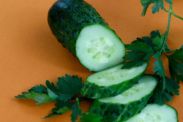 Slices of fresh green cucumber on an orange background. Side view, horizontal, close-up, free space, cropped shot. Healthy eating concept.