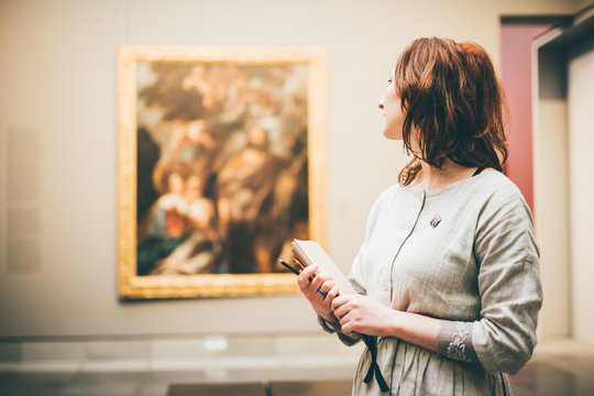 young woman sketching in museum. woman holding the notepad and thinking.