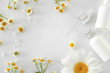 Frame made of cosmetic products with chamomile flowers on white background