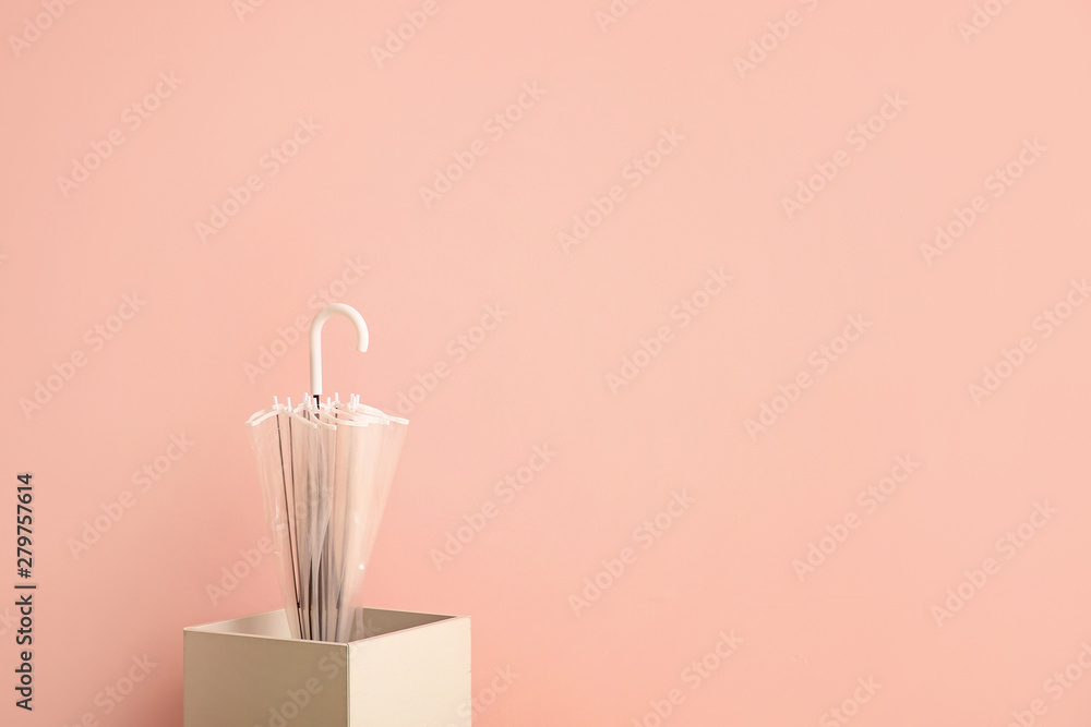 Stylish umbrella with box on color background