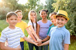 © Pixel-Shot - Group of children putting hands together outdoors