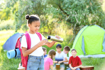 african-american girl with thermos resting at summer camp