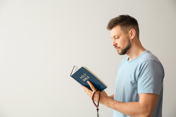 Wall Mural - Religious man reading Bible on light background